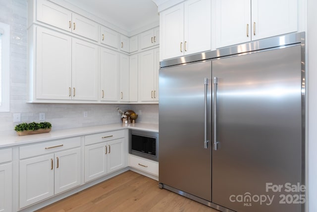 4203 Walker Rd, Charlotte, NC 28211 - kitchen with built in appliances, light countertops, light wood finished floors, white cabinets, and tasteful backsplash