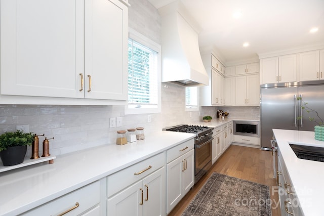 4203 Walker Rd, Charlotte, NC 28211 - kitchen featuring built in appliances, premium range hood, light wood finished floors, white cabinetry, and light countertops