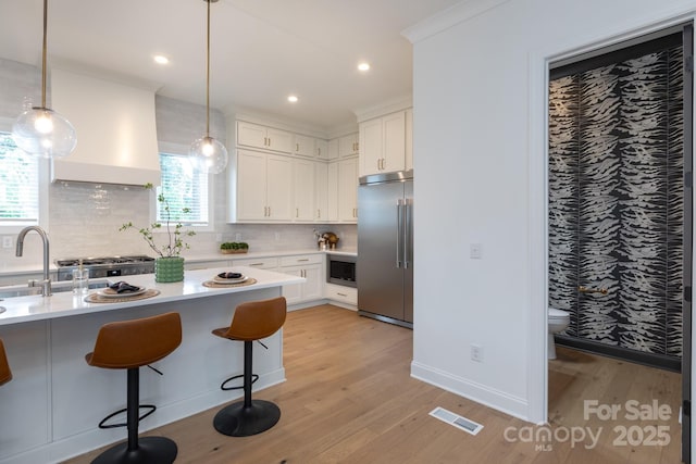 4203 Walker Rd, Charlotte, NC 28211 - kitchen with built in appliances, light wood-style flooring, light countertops, tasteful backsplash, and a kitchen breakfast bar