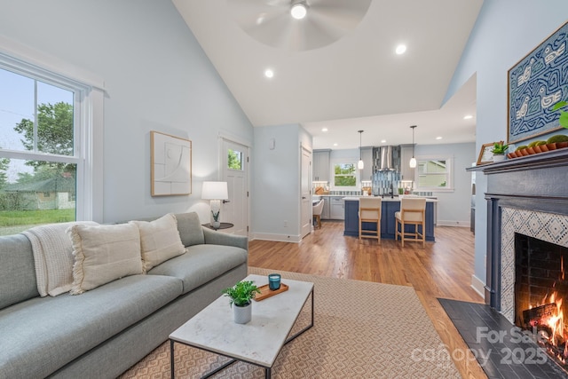 2421 Morton St, Charlotte, NC 28208 - living room featuring high vaulted ceiling, a fireplace, a ceiling fan, light wood-type flooring, and recessed lighting