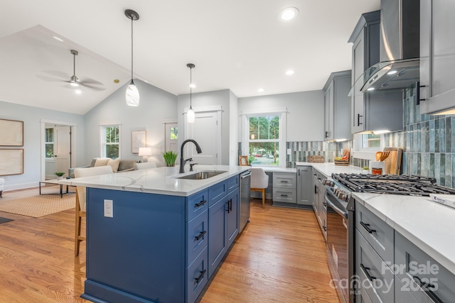 2421 Morton St, Charlotte, NC 28208 - kitchen with stainless steel appliances, a sink, wall chimney range hood, light wood-style floors, and lofted ceiling