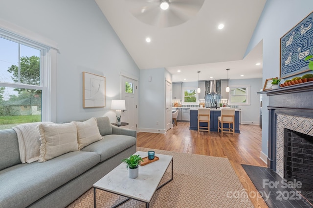 2421 Morton St, Charlotte, NC 28208 - living room with high vaulted ceiling, light wood-type flooring, a ceiling fan, recessed lighting, and a tiled fireplace