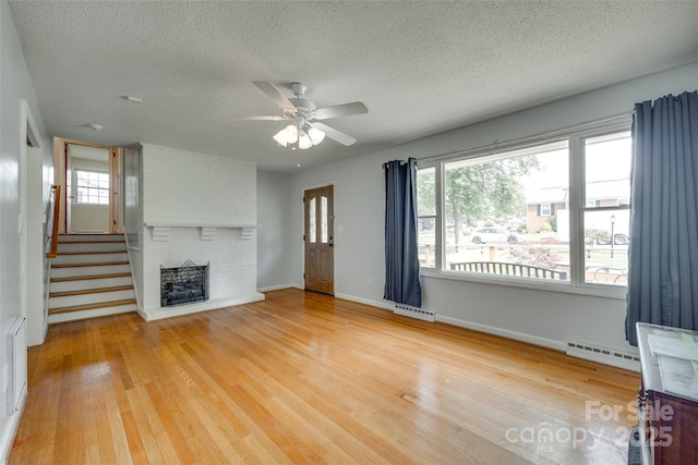 2111 Parkdale Ave, Gastonia, NC 28052 - unfurnished living room featuring a textured ceiling, baseboard heating, wood finished floors, a ceiling fan, and a brick fireplace