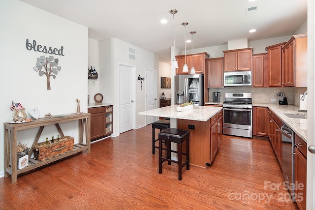 7328 Strawberry Fields Ln, Charlotte, NC 28278 - kitchen featuring stainless steel appliances, a sink, brown cabinets, wood finished floors, and a center island