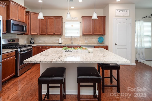 7328 Strawberry Fields Ln, Charlotte, NC 28278 - kitchen with appliances with stainless steel finishes, a breakfast bar, a sink, brown cabinets, and tasteful backsplash