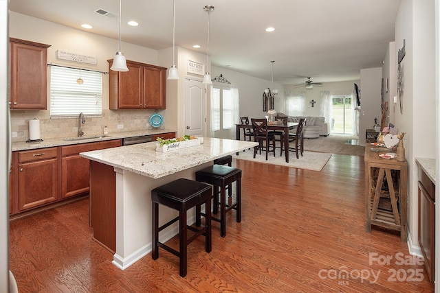 7328 Strawberry Fields Ln, Charlotte, NC 28278 - kitchen featuring a sink, open floor plan, brown cabinetry, dark wood finished floors, and a kitchen bar