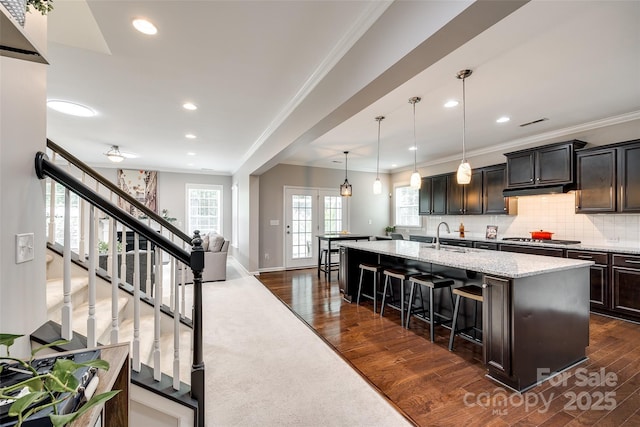 129 Hawks Creek Pkwy, Fort Mill, SC 29708 - kitchen featuring a kitchen bar, ornamental molding, an island with sink, light stone counters, and dark wood finished floors