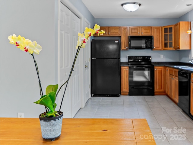 17 Fieldtop Ln, Arden, NC 28704 - kitchen featuring black appliances, dark countertops, light tile patterned floors, glass insert cabinets, and brown cabinetry