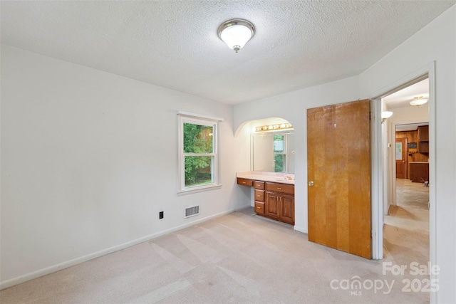 46 Donna Dale Ave SE, Concord, NC 28025 - unfurnished bedroom with light colored carpet, baseboards, a textured ceiling, a sink, and arched walkways