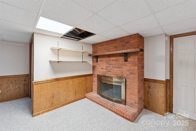 46 Donna Dale Ave SE, Concord, NC 28025 - unfurnished living room featuring wainscoting, a paneled ceiling, a brick fireplace, carpet, and wood walls
