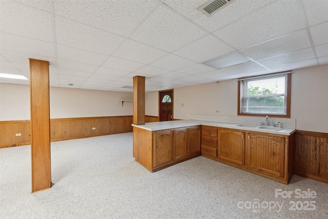 46 Donna Dale Ave SE, Concord, NC 28025 - kitchen featuring a wainscoted wall, a sink, a drop ceiling, brown cabinetry, and wood walls