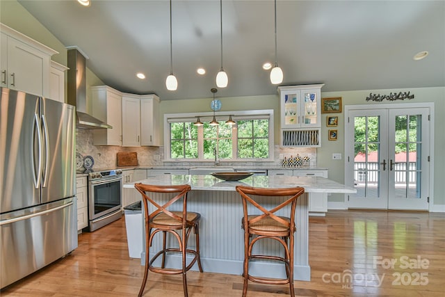 63 Greenridge Rd, Weaverville, NC 28787 - kitchen featuring appliances with stainless steel finishes, wall chimney range hood, white cabinetry, lofted ceiling, and a kitchen breakfast bar