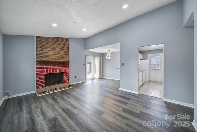 8520 Mission Hills Rd, Charlotte, NC 28227 - unfurnished living room featuring a textured ceiling, light wood-style floors, recessed lighting, and a brick fireplace