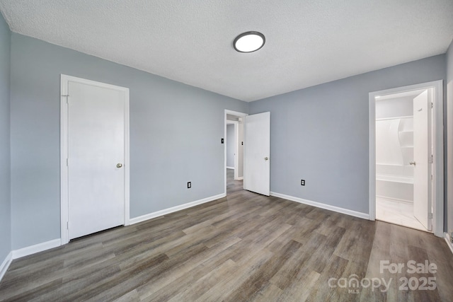 8520 Mission Hills Rd, Charlotte, NC 28227 - unfurnished bedroom with wood finished floors, connected bathroom, and a textured ceiling