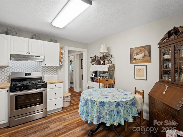 206 Charlotte St, York, SC 29745 - kitchen with stainless steel range with gas stovetop, under cabinet range hood, wood counters, white cabinetry, and light wood-style flooring