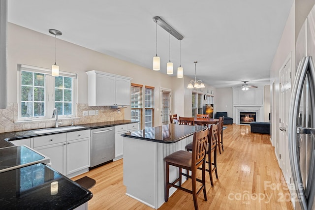 3830 Waters Reach Ln, Indian Trail, NC 28079 - kitchen featuring appliances with stainless steel finishes, a ceiling fan, light wood finished floors, backsplash, and a breakfast bar