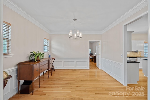 3830 Waters Reach Ln, Indian Trail, NC 28079 - dining room featuring a chandelier, ornamental molding, light wood-type flooring, a decorative wall, and wainscoting