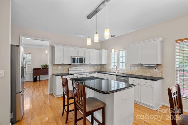 3830 Waters Reach Ln, Indian Trail, NC 28079 - kitchen featuring stainless steel appliances, white cabinets, light wood finished floors, decorative backsplash, and a breakfast bar area