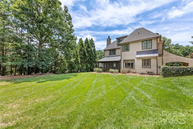 1728 Shadow Forest Dr, Matthews, NC 28105 - back of property featuring a standing seam roof, a chimney, stucco siding, and a lawn