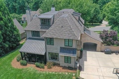 1728 Shadow Forest Dr, Matthews, NC 28105 - back of property featuring stucco siding, concrete driveway, a chimney, a garage, and a standing seam roof