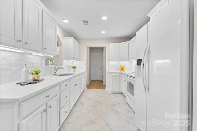 3008 Cornflower Ln, Indian Trail, NC 28079 - kitchen with white appliances, recessed lighting, white cabinetry, tasteful backsplash, and light marble finish floors