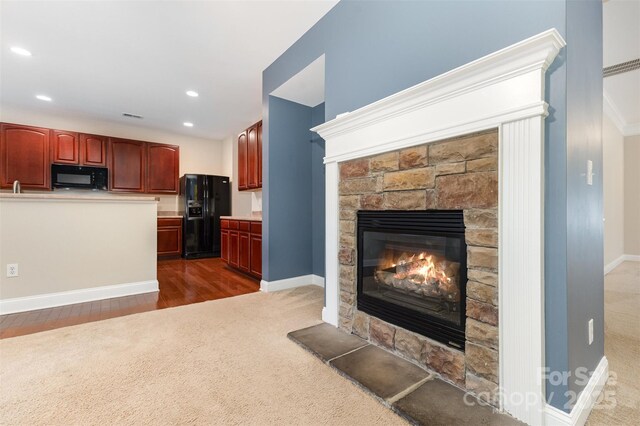 237 Lylic Woods Dr, Fort Mill, SC 29715 - kitchen with black appliances, a stone fireplace, dark wood-type flooring, dark colored carpet, and recessed lighting