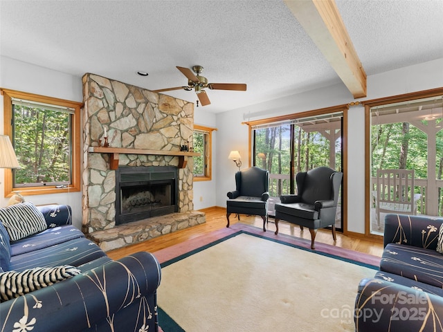 43 Hungryneck Hollow Ln, Saluda, NC 28773 - living area with wood finished floors, a textured ceiling, a ceiling fan, a stone fireplace, and baseboards