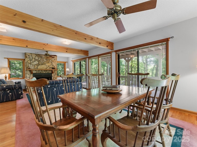 43 Hungryneck Hollow Ln, Saluda, NC 28773 - dining room featuring light wood-type flooring, a ceiling fan, beam ceiling, baseboards, and a stone fireplace