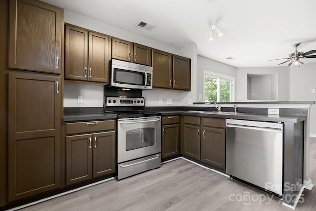 7315 Gasper Ln, Fort Mill, SC 29707 - kitchen with appliances with stainless steel finishes, a peninsula, a sink, dark countertops, and light wood finished floors