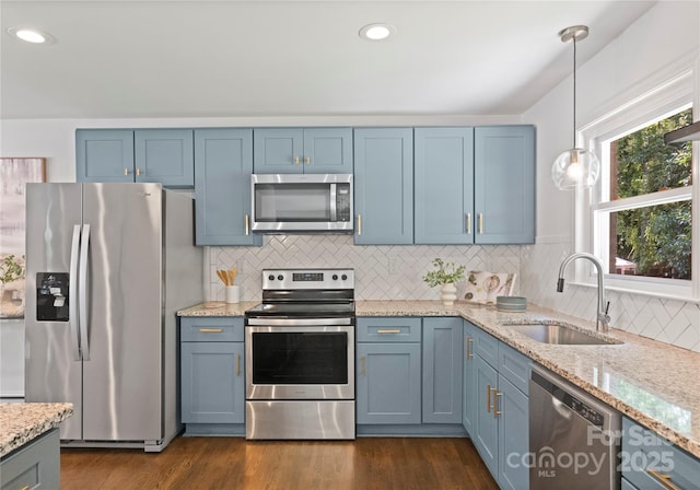1027 Dresden Dr W, Charlotte, NC 28205 - kitchen with appliances with stainless steel finishes, blue cabinets, light stone countertops, decorative backsplash, and hanging light fixtures
