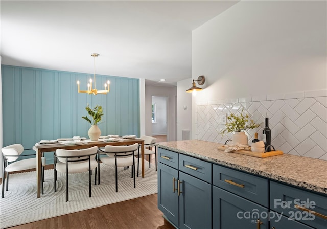 1027 Dresden Dr W, Charlotte, NC 28205 - kitchen with dark wood finished floors, a chandelier, hanging light fixtures, tasteful backsplash, and light stone counters