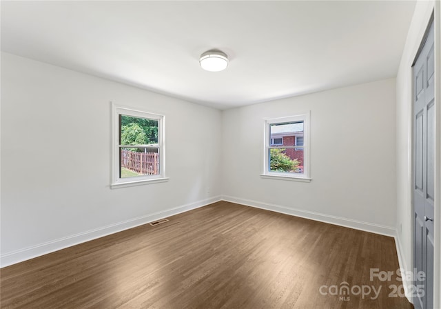 1027 Dresden Dr W, Charlotte, NC 28205 - unfurnished bedroom featuring dark wood finished floors, multiple windows, and a closet
