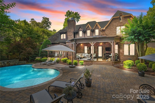 617 Beauhaven Ln, Waxhaw, NC 28173 - back of house at dusk featuring a patio area, an outdoor pool, a gazebo, and a chimney