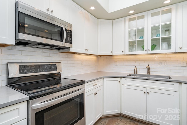 5742 Murrayhill Rd, Charlotte, NC 28210 - kitchen featuring appliances with stainless steel finishes, white cabinetry, recessed lighting, glass insert cabinets, and light countertops