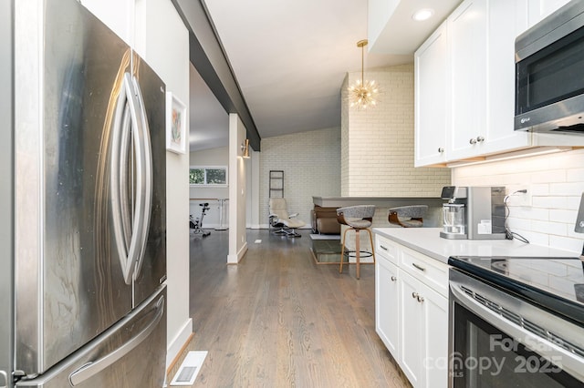5742 Murrayhill Rd, Charlotte, NC 28210 - kitchen featuring appliances with stainless steel finishes, wood finished floors, white cabinetry, decorative backsplash, and hanging light fixtures