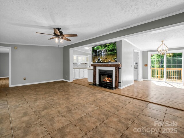 2941 Nix Creek Rd, Marion, NC 28752 - unfurnished living room featuring a textured ceiling, ceiling fan, a warm lit fireplace, a chandelier, and ornamental molding