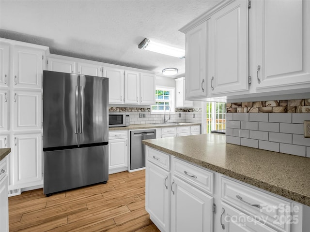 2941 Nix Creek Rd, Marion, NC 28752 - kitchen featuring appliances with stainless steel finishes, white cabinets, decorative backsplash, a sink, and a textured ceiling