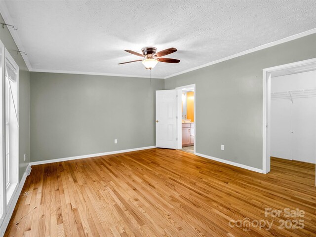 2941 Nix Creek Rd, Marion, NC 28752 - unfurnished bedroom featuring light wood-type flooring, baseboards, a walk in closet, a textured ceiling, and ornamental molding