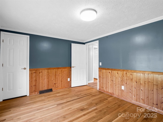 2941 Nix Creek Rd, Marion, NC 28752 - unfurnished room with wainscoting, wood finished floors, a textured ceiling, wood walls, and ornamental molding