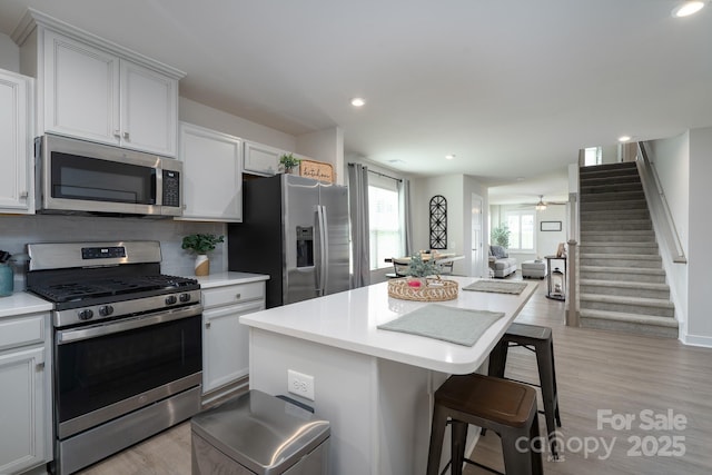 154 Stella Ln Unit A, Troutman, NC 28166 - kitchen with appliances with stainless steel finishes, a breakfast bar area, a kitchen island, light countertops, and tasteful backsplash