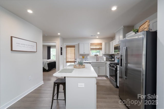 154 Stella Ln Unit A, Troutman, NC 28166 - kitchen with appliances with stainless steel finishes, a breakfast bar, a kitchen island, decorative backsplash, and recessed lighting
