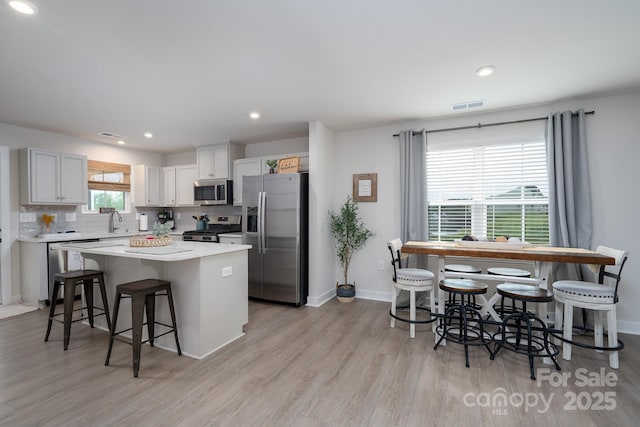 154 Stella Ln Unit A, Troutman, NC 28166 - kitchen with stainless steel appliances, a center island, a breakfast bar area, light wood-type flooring, and backsplash