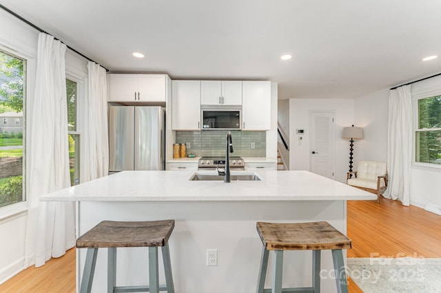 4014 Sulkirk Rd, Charlotte, NC 28210 - kitchen with stainless steel appliances, light wood-style floors, a breakfast bar area, decorative backsplash, and white cabinetry