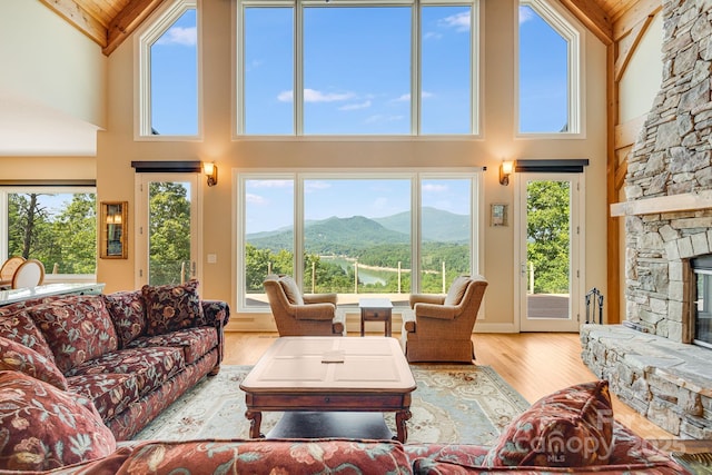 122 Eagles Crest Way, Lake Lure, NC 28746 - living area featuring high vaulted ceiling, a stone fireplace, a wood ceiling with exposed beams, wood finished floors, and plenty of natural light
