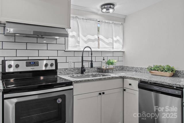 405 E 18th St, Kannapolis, NC 28083 - kitchen with stainless steel appliances, tasteful backsplash, white cabinetry, light stone countertops, and extractor fan