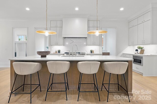 1321 Ferncliff Rd, Charlotte, NC 28211 - kitchen featuring custom exhaust hood, light countertops, recessed lighting, a kitchen island with sink, and white cabinetry