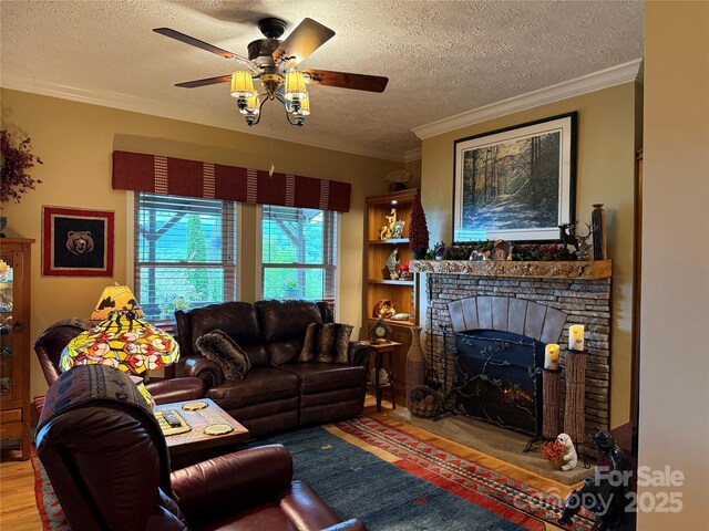 394 Hummingbird Ln, Elk Park, NC 28622 - living room with ceiling fan, a textured ceiling, ornamental molding, a stone fireplace, and wood finished floors