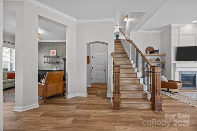 11329 Fullerton Place Dr NW, Huntersville, NC 28078 - stairway with ornamental molding, arched walkways, a glass covered fireplace, and wood finished floors