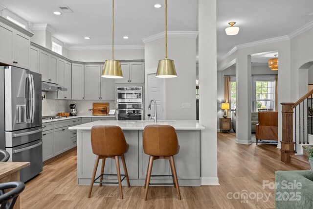 11329 Fullerton Place Dr NW, Huntersville, NC 28078 - kitchen with appliances with stainless steel finishes, under cabinet range hood, a breakfast bar area, gray cabinetry, and light wood-type flooring