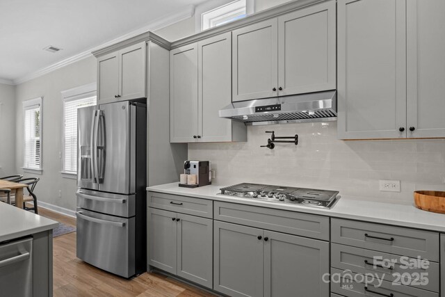 11329 Fullerton Place Dr NW, Huntersville, NC 28078 - kitchen with appliances with stainless steel finishes, under cabinet range hood, gray cabinets, ornamental molding, and light countertops